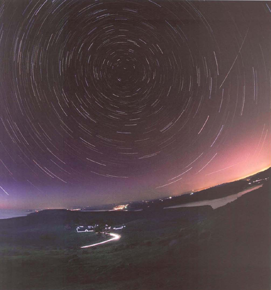 On a relatively balmy November evening shortly after sunset, I drove out to the end of the North Fork of the Point Reyes, California, peninsula. I pointed my camera due north for maximum star circles and lined up the historic Pierce Farm with Polaris. My plan was to stack at least twelve exposures as a composite and to use the lightest version for the fore ground. My first exposure was, in fact, the lightest version, since a bit of light from the sun set lingered. So once I had created my stack, I separately composited the foreg round from this version on to my stack. As the camera did all the work, it was pleasant lying back on the grass, talking stars and philosophy with my oldest son, who had come along.: 10.5mm digital fisheye, stacked composite of fifteen exposures, each capture 4 minutes at f/4 and ISO 200, tripod mounted, total exposure time 1 hour