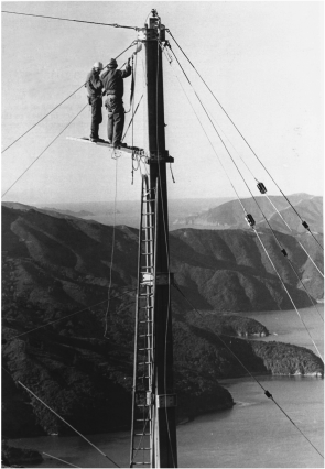Picture taken approximately 100 years back in New Zealand. Two persons were seen mounted on a wooden plank during the construction of a tower to support the power cable across the Tory Channel in the Marlborough Sounds.