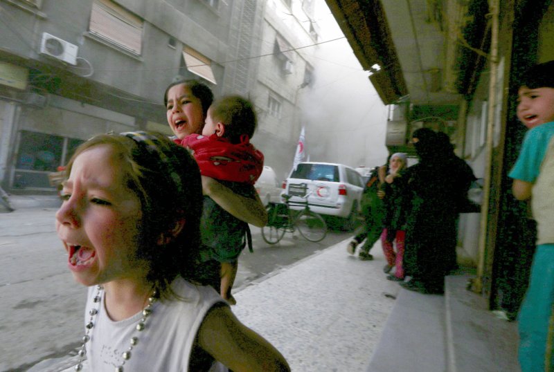 Photo shows children and adults crying and running away from smoked area.